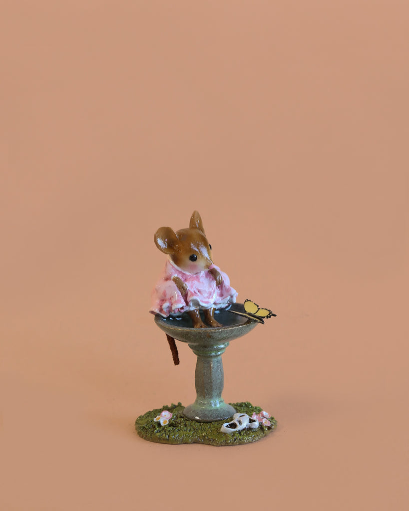 The Wee Forest Folk Tiny Collectible - Garden Spa features a hand-sculpted mouse in a pink dress with eyeglasses, perched on a flower-adorned birdbath, and set against a plain peach background.