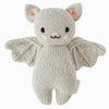 The Cuddle + Kind Baby Limited Edition Grey Bat is a knitted plush toy in the shape of a bat, crafted from light gray Peruvian cotton yarn. It features pink ears, black stitched eyes and mouth, and spread-open wings. A small tag is attached to its side. This hand-knit collectible stands out against the plain white background.