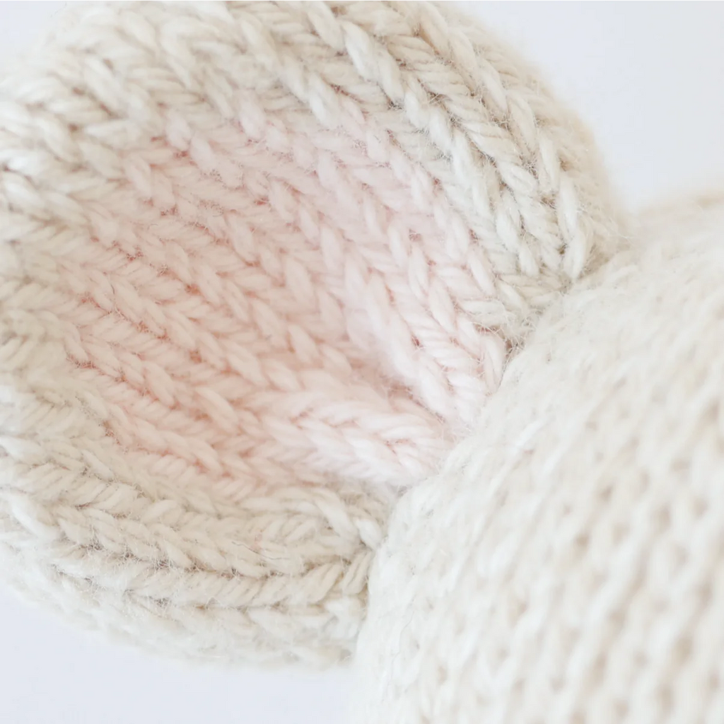 Close-up of the Cuddle + Kind Baby Mouse’s ear, hand-knit with cream-colored Peruvian cotton yarn on the outside and light pink inside, showcasing sustainable fair trade craftsmanship in every stitch.