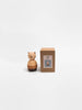The Sabo Concept Bear Stacker - Beige, a small wooden toy with a round body, stands beside its brown box displaying its image, all set against a plain white background.