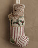 The Coral & Tusk Puppy Stocking Ornament features an embroidered puppy with holly leaves and red stripes, bringing a cheerful holiday touch to your décor when hung against a beige wall.