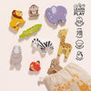 Africa Stacking Animals & Bag features colorful wooden lion, monkey, and elephant figures near a fabric bag. This sustainable toy helps develop fine motor skills, with educational icons and phrases displayed on the right.