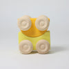 A Grimm's Stacking Cars - Yellow toy, featuring a yellow wooden body and four light-colored round wheels, is displayed against a plain white background.
