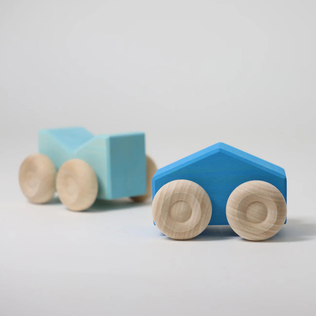 Two Grimm's Stacking Cars - Blue, one light and one dark, each with four natural wood wheels, are displayed on a plain white surface against a minimal background.