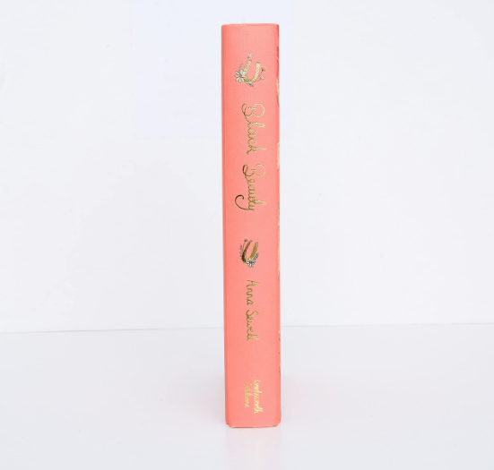 The Black Beauty | Collector's Edition | Hardcover features a pink cover with gold illustrations and decorative lettering of the title and Anna Sewell's name on the spine, displayed upright against a plain white background.