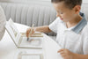 A young boy uses a water-filled pen to color a birthday cake illustration in a Winnie-the-Pooh: Pooh’s Birthday Surprise (Water Reveal) book.