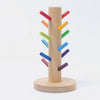 Grimm's Sorting Helper with Building Rings Set features a wooden base and central post, with colorful red, orange, yellow, green, blue, and purple pegs spiraling diagonally to boost fine motor skills. Inspired by Grimm's Building Rings.
