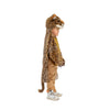 A young child stands in profile wearing the Costume - Leopard, which features a faux fur design with a hood, tail, and paw-like gloves. The background is plain white.