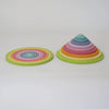 Two sets from Grimm's Concentric Circles and Rings Building Set - Pastel are displayed on a white surface: one arranged in stacked concentric rings, the other built vertically into a cone, showcasing the colorful wooden discs.