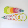 The Grimm's Concentric Circles and Rings Building Set - Pastel features colorful wooden discs and matching open rings in graduating sizes, ideal for creative balance games and imaginative building play.