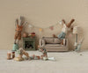 Several toy rabbits decorate a room with bunting, gifts, and a Maileg Miniature Cakes & Cake Stand.