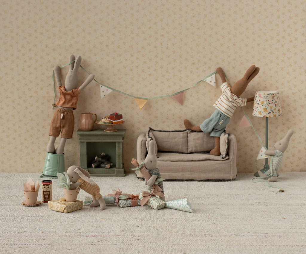 Several toy rabbits decorate a room with bunting, gifts, and a Maileg Miniature Cakes & Cake Stand.