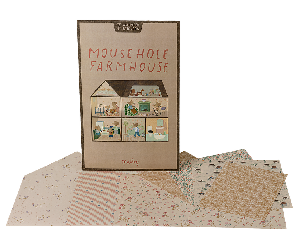 A Maileg Farmhouse Dollhouse with Wallpaper box standing behind several sheets of patterned wallpaper stickers.