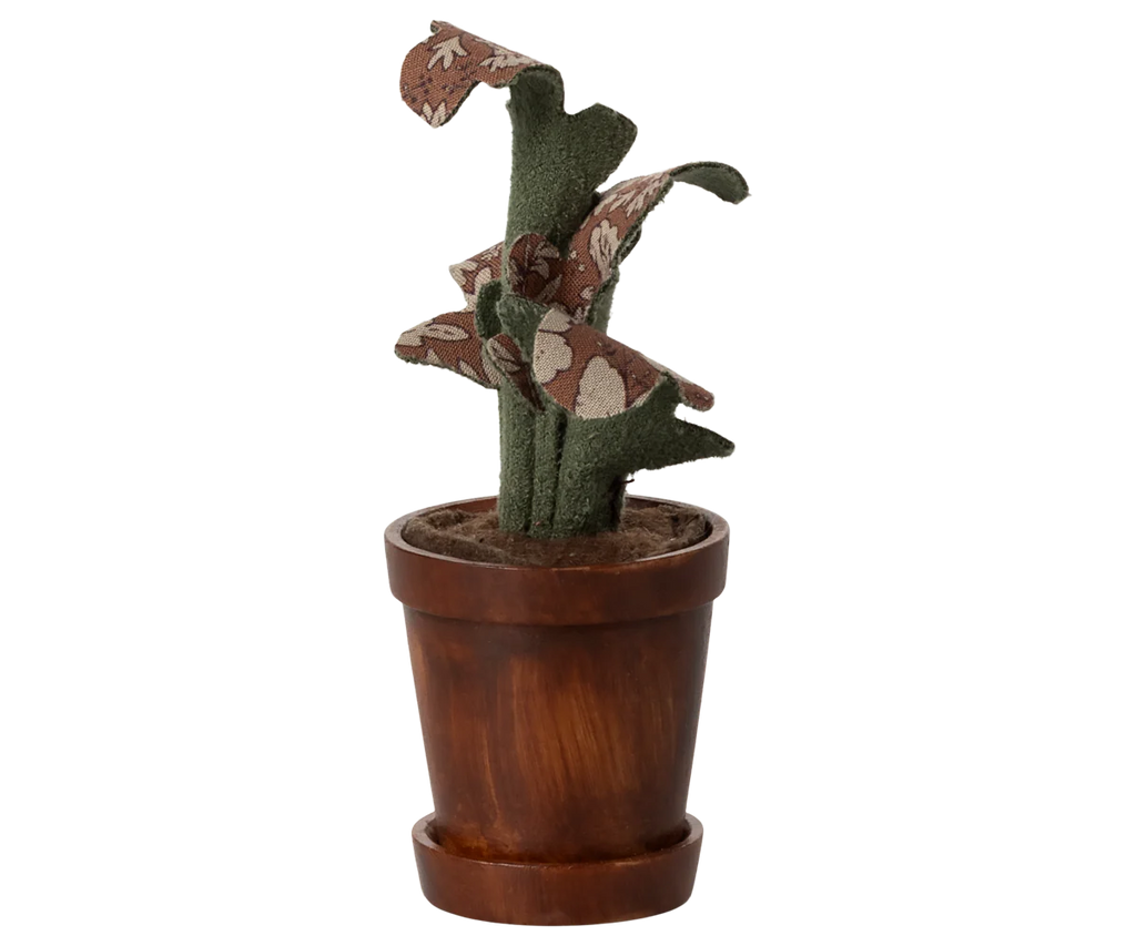 The Maileg Flower Pot With Plant, Miniature features green and brown floral-patterned leaves in a wooden pot, set against a blurred striped background.