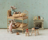 Two magnetic Maileg Waffle Set, Mouse toy mice rest in a bunk bed beside a miniature fireplace, with a stool holding a wafflemaker play set and a jar of jam.