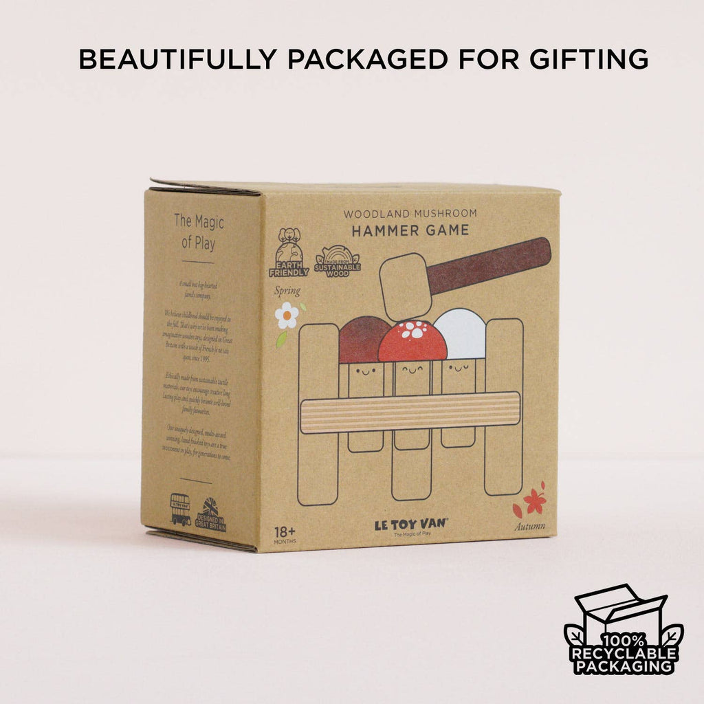 The Woodland Mushroom Hammer Game by Le Toy Van comes in a 100% recyclable cardboard box with playful mushroom designs, displayed on a white surface. This wooden toy is perfect for gifting and helps develop fine motor skills.