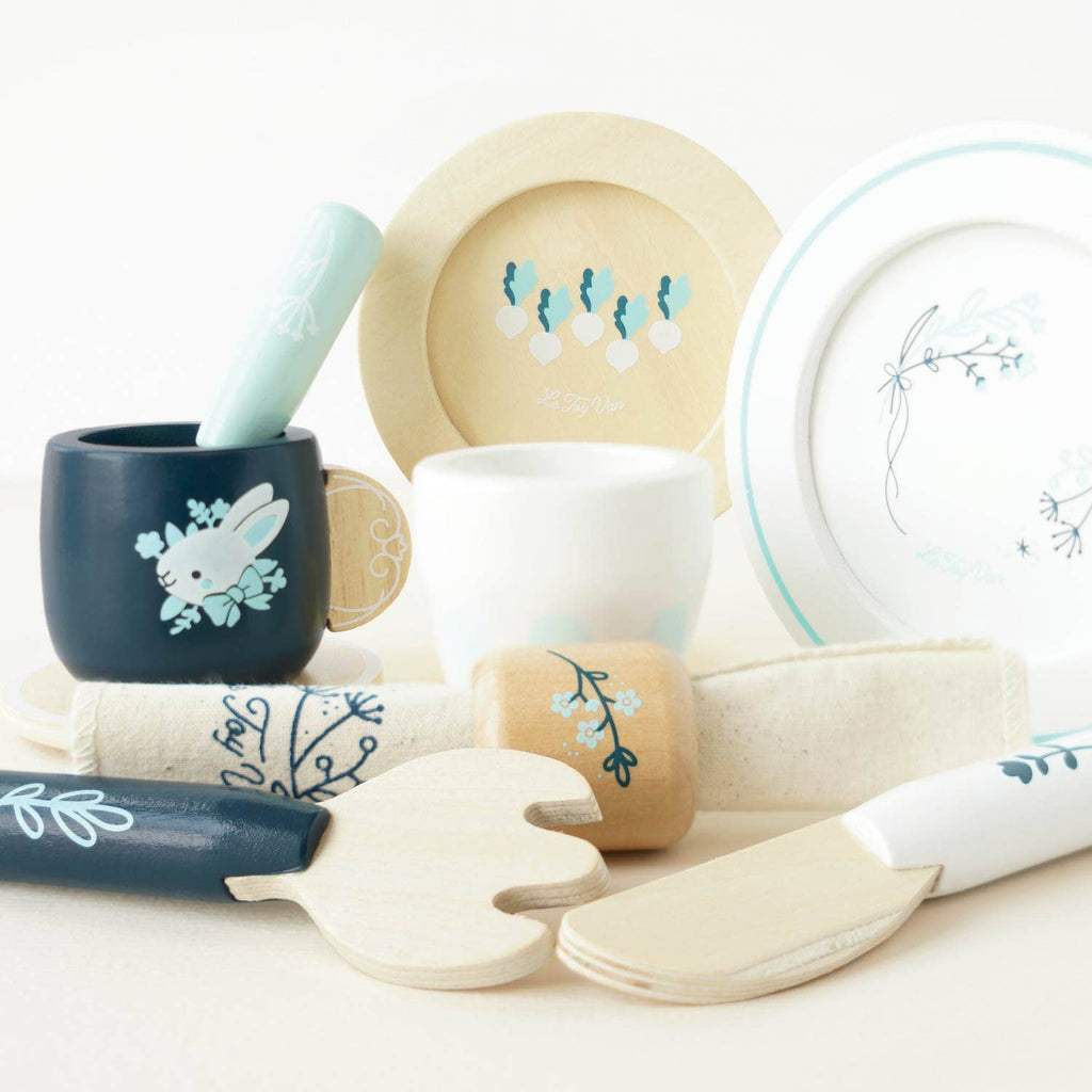 A Cutlery & Dinner Set for pretend play featuring a wooden mug, plates, a napkin ring, and toy cutlery decorated with floral and rabbit patterns.