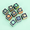 Twelve Uncle Goose Planet Blocks, each with a different solar system planet motif, arranged haphazardly on a light green background.