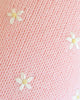Close-up of Cuddle + Kind Sophia the Pony’s soft pink knitted fabric, handmade in Peru and adorned with small white embroidered flowers with yellow centers for a delicate, cozy look.