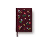 The Gracie Mini Embroidered Journal in burgundy features colorful floral and leaf embroidery, blank unlined pages, and a matching ribbon bookmark, displayed against a white background.