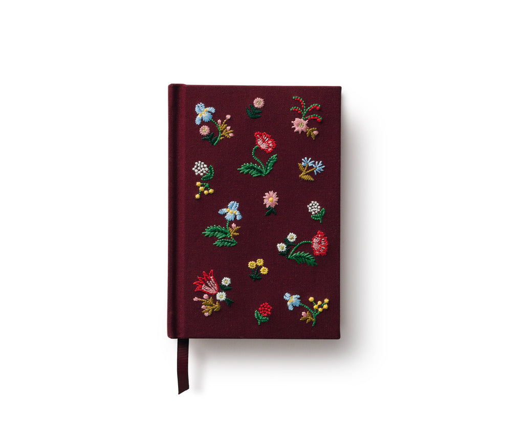 The Gracie Mini Embroidered Journal in burgundy features colorful floral and leaf embroidery, blank unlined pages, and a matching ribbon bookmark, displayed against a white background.