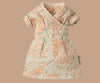 The Maileg Mom Mouse With Extra Outfit - Petite Couture showcases a delightful wrap-over dress with short sleeves, lace trim, and an orange floral pattern on light teal, perfect for dressing Maileg Mum Mouse in charming elegance against a beige background.