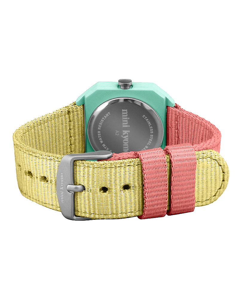 The Mini Kyomo Watch - Bubble Gum features a teal case, silver back, and reversible yellow-pink fabric strap with a silver buckle—a playful pastel kids watch.