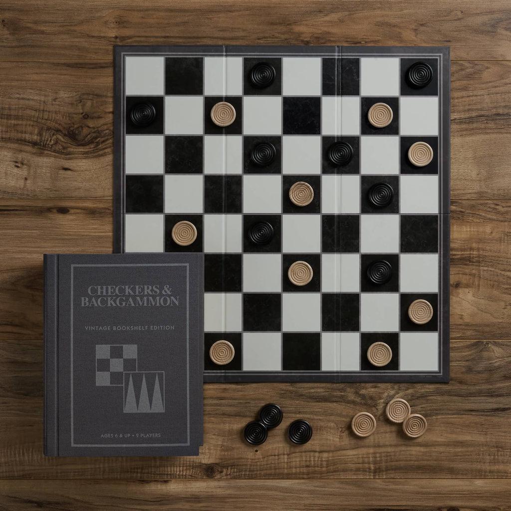 A checkers board with black and tan pieces is set on a wooden table. Beside it is the Board Game: Checkers & Backgammon Vintage Bookshelf Edition, ideal for game enthusiasts, with extra pieces scattered nearby.
