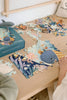 A person assembles the 100-piece "Tales from the Deep" puzzle, designed for ages 5+, on a wooden table. The ocean-themed puzzle features sea animals like a blue whale and fish, with its illustrated box and a toy shark nearby.