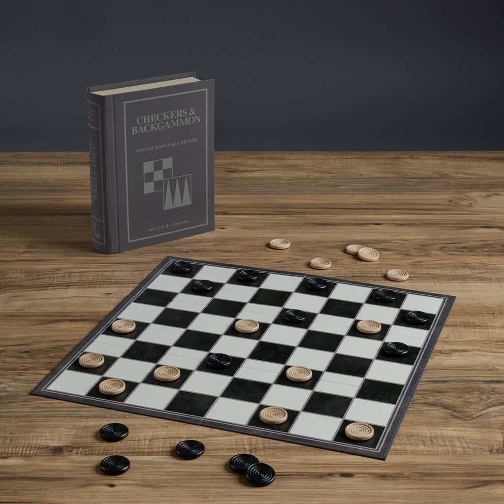 The Board Game: Checkers & Backgammon Vintage Bookshelf Edition features a black-and-white board with black and beige pieces, presented in a closed, upright book-style case on a wooden table—perfect for fans of classic games.