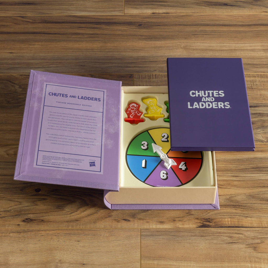 The Chutes and Ladders Vintage Bookshelf Edition is open on a wooden surface, showing the game spinner and colorful pieces. The box lid rests nearby, with instructions printed inside.