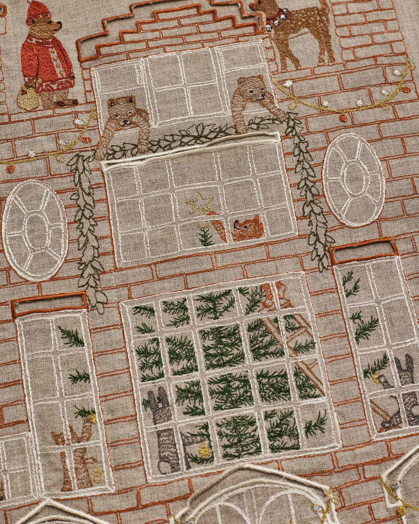 Coral & Tusk Holiday House Advent Calendar made of embroidered linen, featuring a brick house with various animals in windows and rooms.