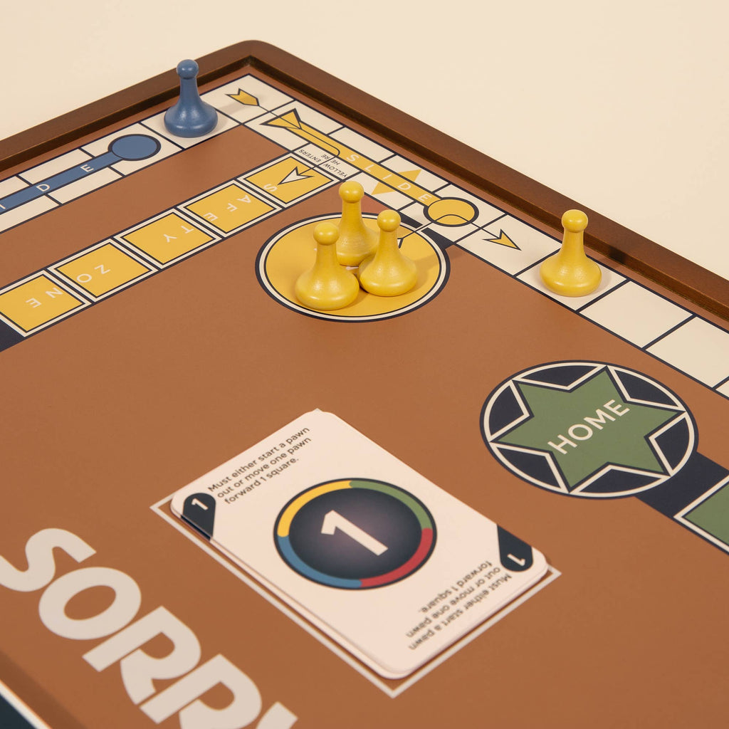 A 3-in-1 Game Collection featuring Monopoly, Sorry & Mancala is shown with yellow and blue pawns on the Sorry! board and a number 1 card near "HOME," set on a brown background—ideal for classic game enthusiasts' cabinets.
