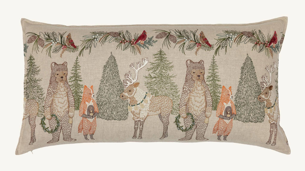 Coral & Tusk Christmas Cheer Lumbar Pillow featuring embroidered bears, foxes, and reindeer holding wreaths amidst pine trees, with a festive greenery and cardinal border along the top.
