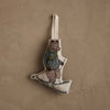 The Coral & Tusk Downhill Bear Ornament features a skiing bear in a striped sweater and scarf with poles, adding a playful winter touch as it hangs by a loop against a textured beige wall.