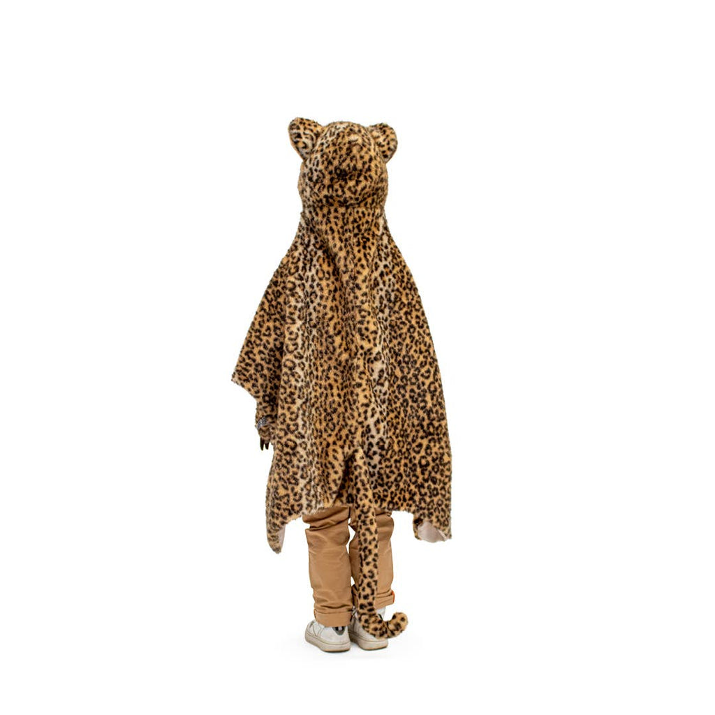 A child faces away wearing the Costume - Leopard, a faux fur hooded cape with ears and tail, over tan pants and white shoes, set against a white background.