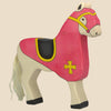 The Holztiger Tournament Horse, Red (ships in one week), is a handcrafted wood figurine with pink covering, yellow trim and cross, white mane and tail, black hooves, and a white face set against a plain background.