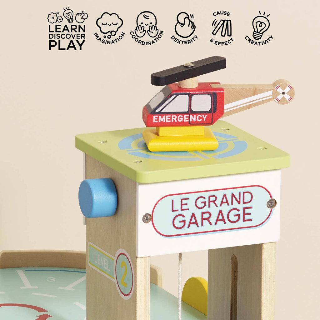 The Le Grand Wooden Garage features a wooden emergency helicopter on a green "LE GRAND GARAGE" platform, highlighting imaginative play, creativity, and coordination skills for kids.