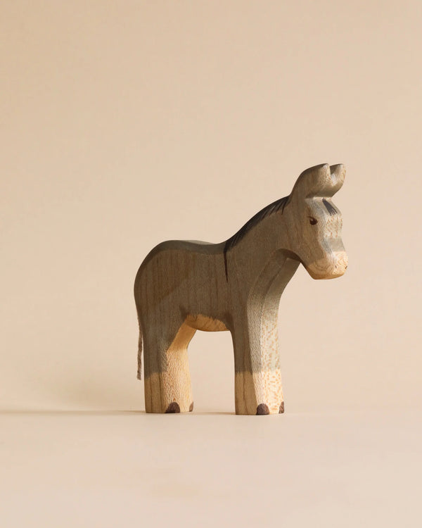 A minimalist, sustainable Handmade Holzwald Donkey toy with a grey body and lighter natural wood legs.