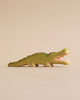 A Handmade Holzwald Crocodile on a plain beige background, standing with its mouth open, showcasing detailed carvings and a smooth green finish.