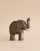 A handmade wooden elephant figurine from the Handmade Holzwald Safari Animals Set with its trunk raised.