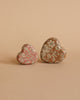 Two heart-shaped objects, including the Maileg Easter Egg with Micro Rabbit & Heart Set—one pink and one brown—are placed side by side on a matching beige background.