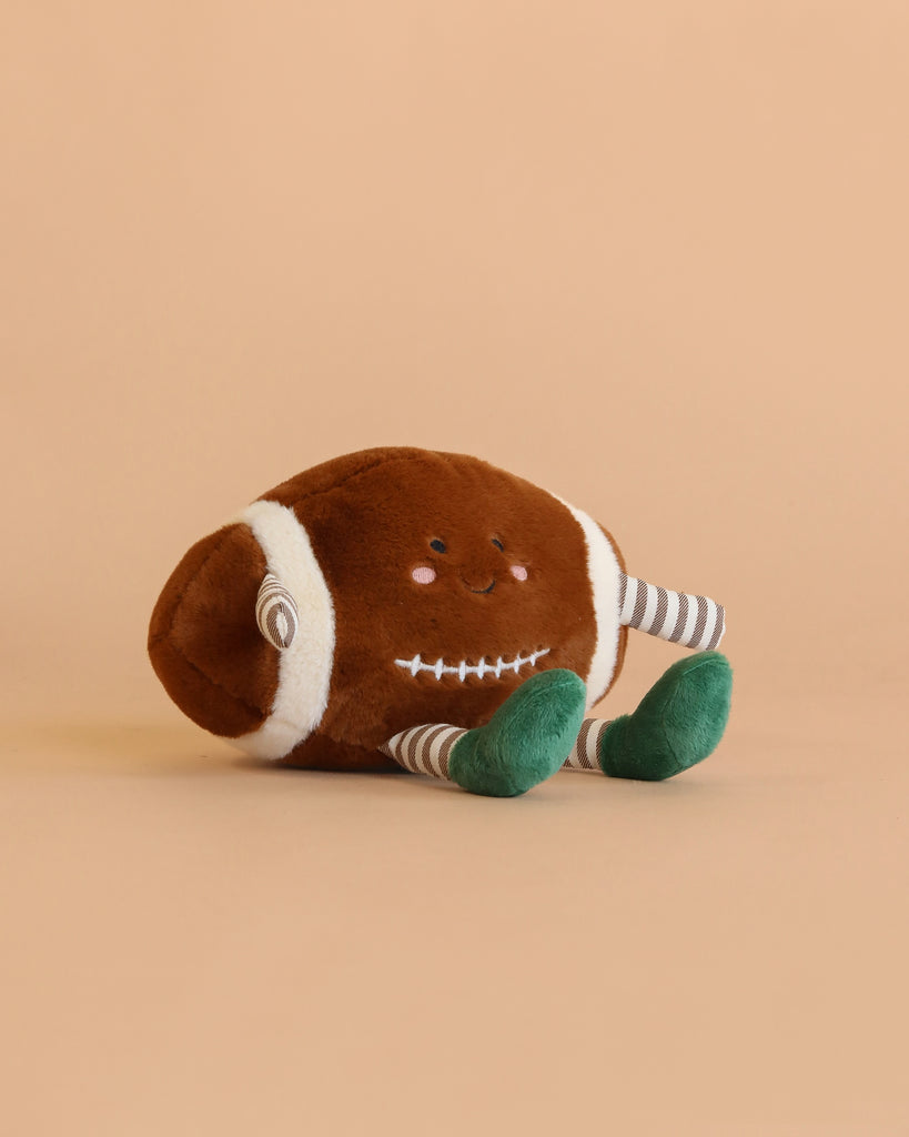 The Mon Ami Sports Ball Set features a football-shaped plush toy with a smiling face, striped arms, and green feet, displayed on a beige background.