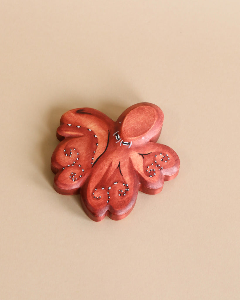 A Handmade Holzwald Octopus wooden butterfly hair clip with carved details and tiny sparkly embellishments, displayed on a beige background.