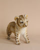A Lion Cub Standing Stuffed Animal stands on a neutral background. The toy, part of our collection of realistic plush animals, has soft light brown fur with subtle darker spots and a detailed expression, giving it a lifelike appearance.