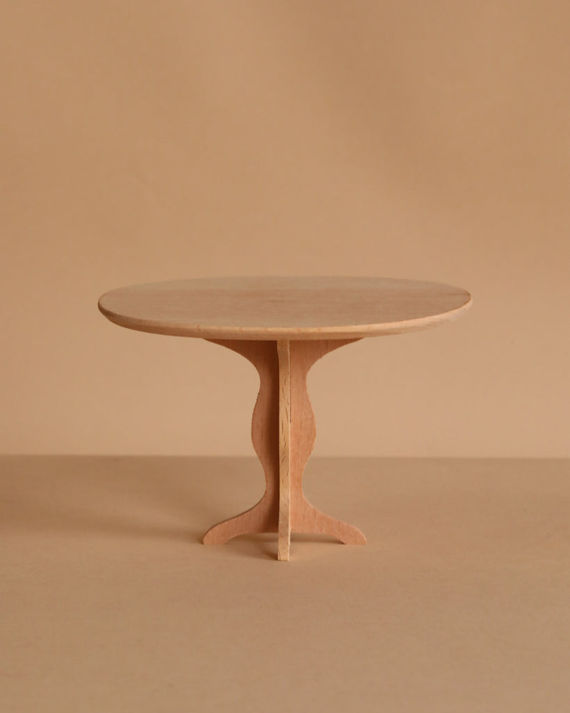 The Maileg Oval Dining Table, Miniature - Bunny/Rabbit Size features a small, round wooden design with a single pedestal base, highlighting fine craftsmanship against a plain beige background.