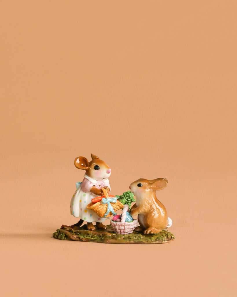 The Wee Forest Folk Tiny Collectible - Baskets Full of Easter Joy features a handmade mouse in a polka-dot dress with a basket, standing beside a rabbit and another basket on a green base against a peach background.