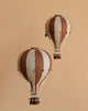 The Hot Air Balloon - Dark Brown features brown and beige stripes with a small basket and decorative ropes, hanging against a beige background—an ideal whimsical touch for decorating a child's room.