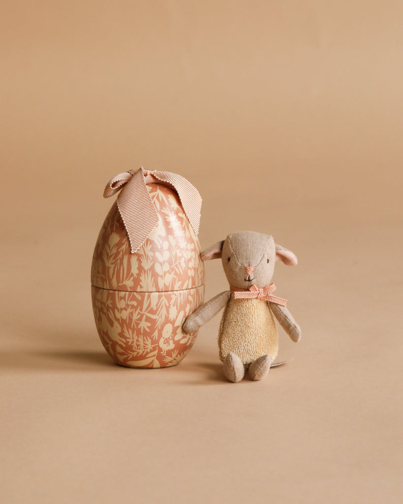 The Maileg Easter Egg with Micro Lamb, Small - Powder, features a cute micro lamb and comes in a decorative egg-shaped box with a bow—an adorable gift for children.