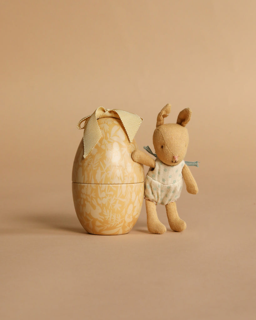 The Maileg Easter Egg & Friends Set features a plush Micro Rabbit in a polka dot outfit alongside a floral-patterned Easter Egg with ribbon, all displayed against a matching beige background.